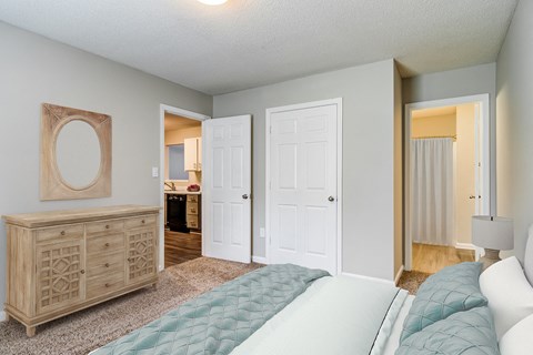 a bedroom with a bed and a dresser and a bathroom